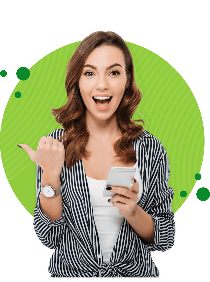 Młoda dziewczyna trzymająca w jednej ręce smartfon, drugą ręką wskazuje kierunek w prawo, w tle za nią jest zielone kółko