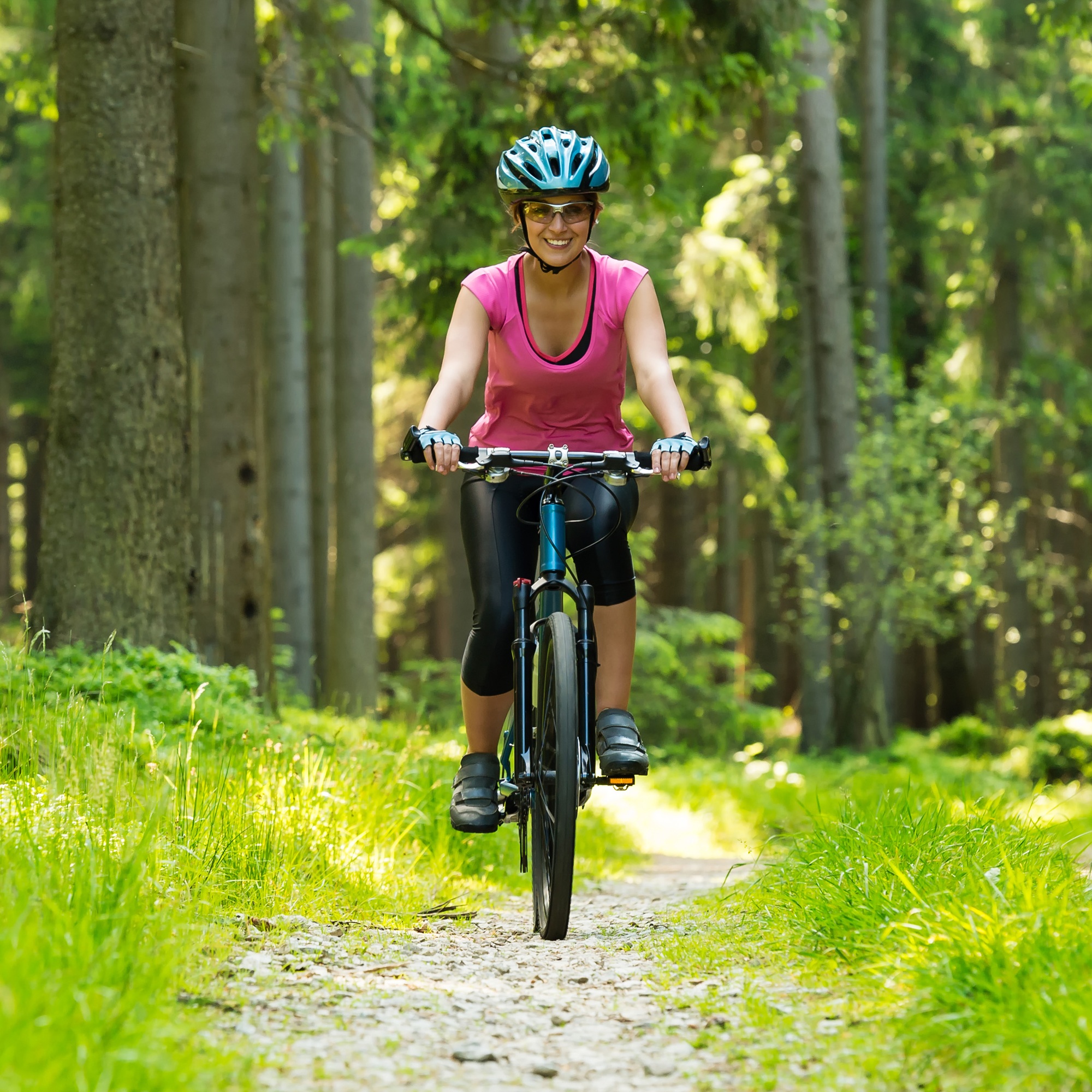 Młoda, wesoła kobieta jedzie rowerem w lesie