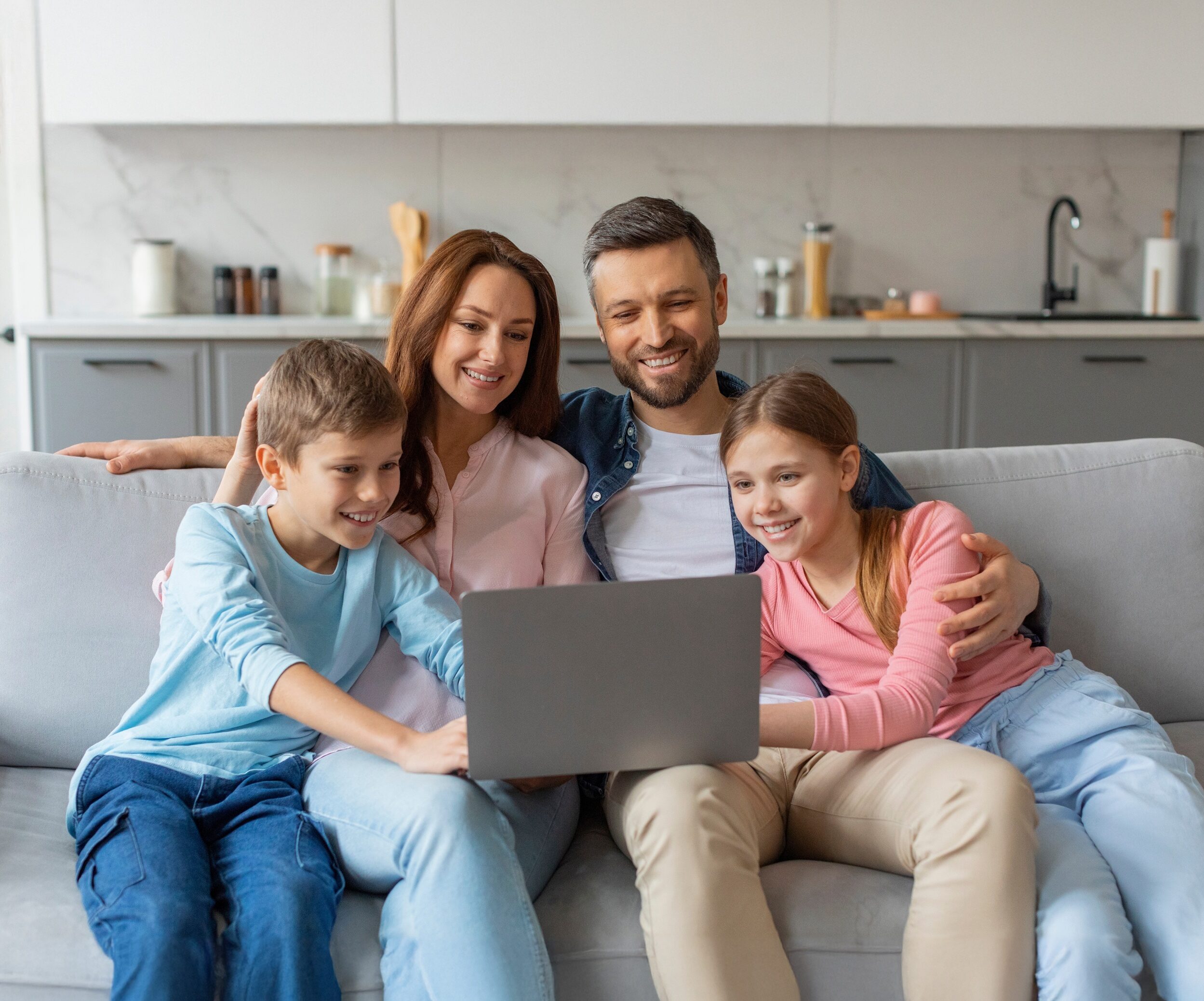 Rodzina siedzi na kanapie i wspólnie korzystają z laptopa